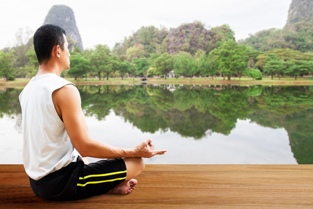 asian man meditating outdoors