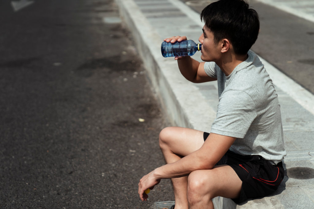asian man drinking water from a bottle