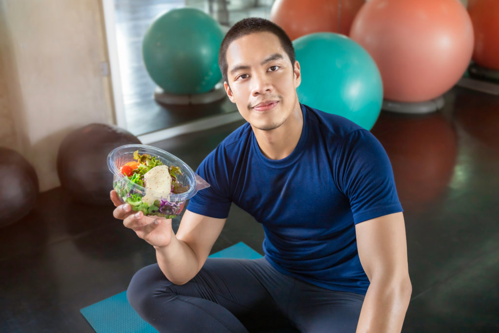 asian man holding a salad bowl in the gym