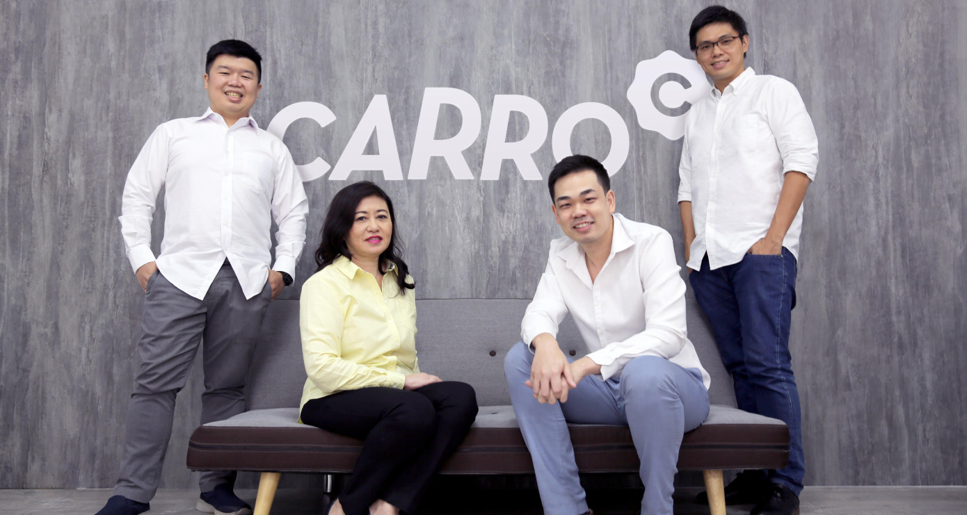 Carro management team in front of Carro logo
