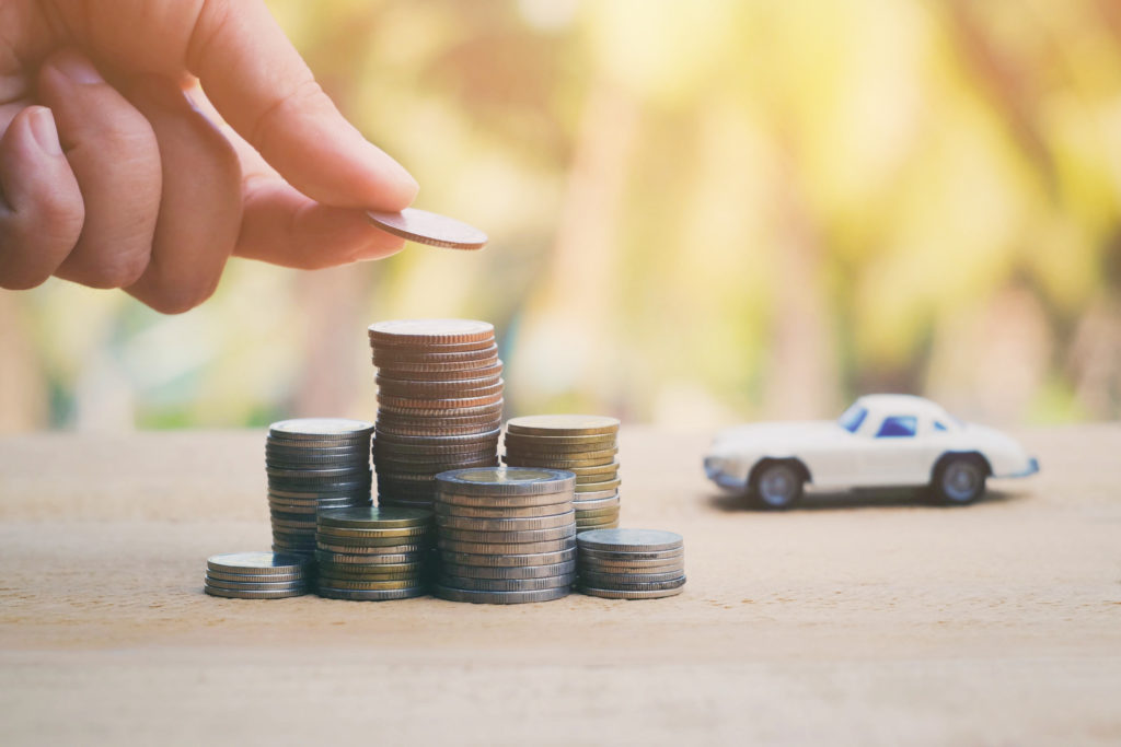 A bunch of coins stacked up with a car in the background