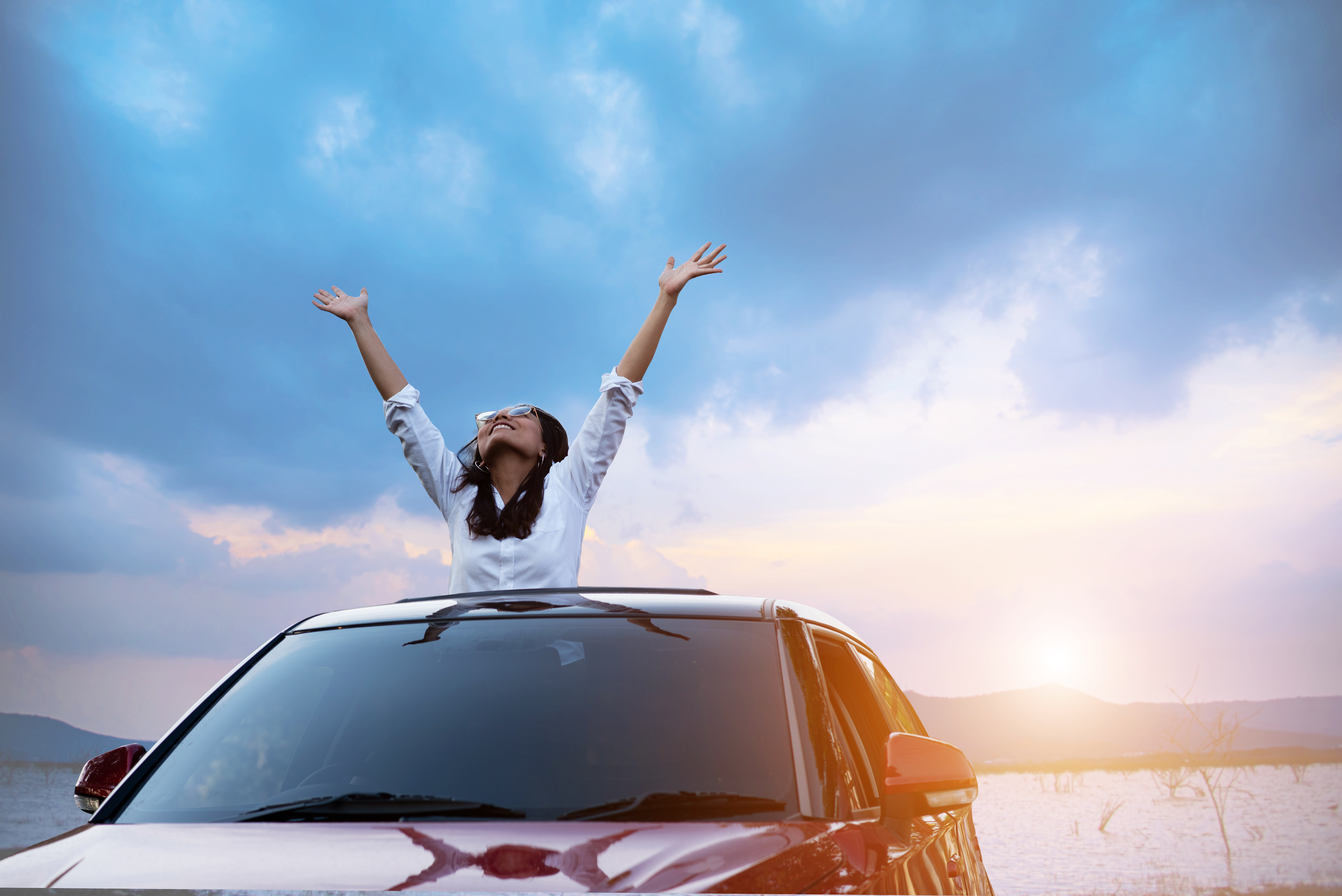 asian lady in a car with hands raised