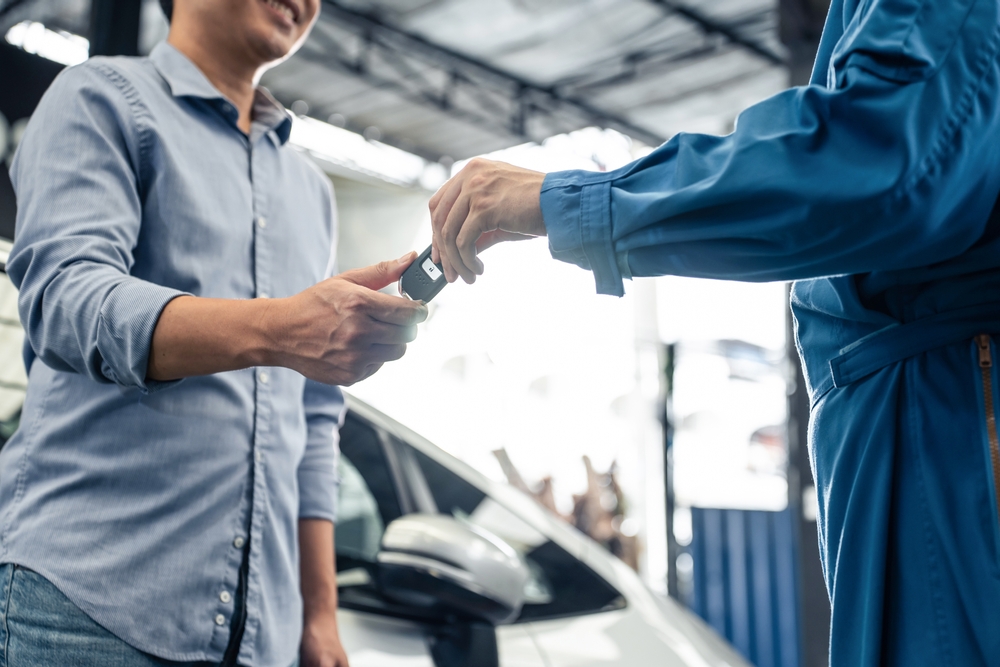 Man handing car keys over to another man 