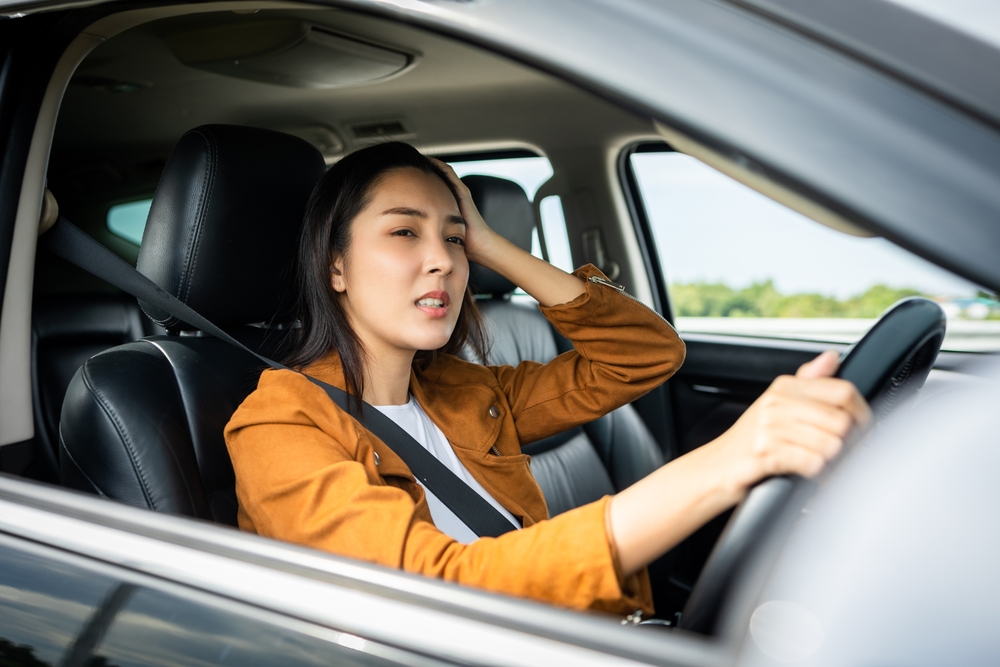 Woman looking stressed in car because of COE hike